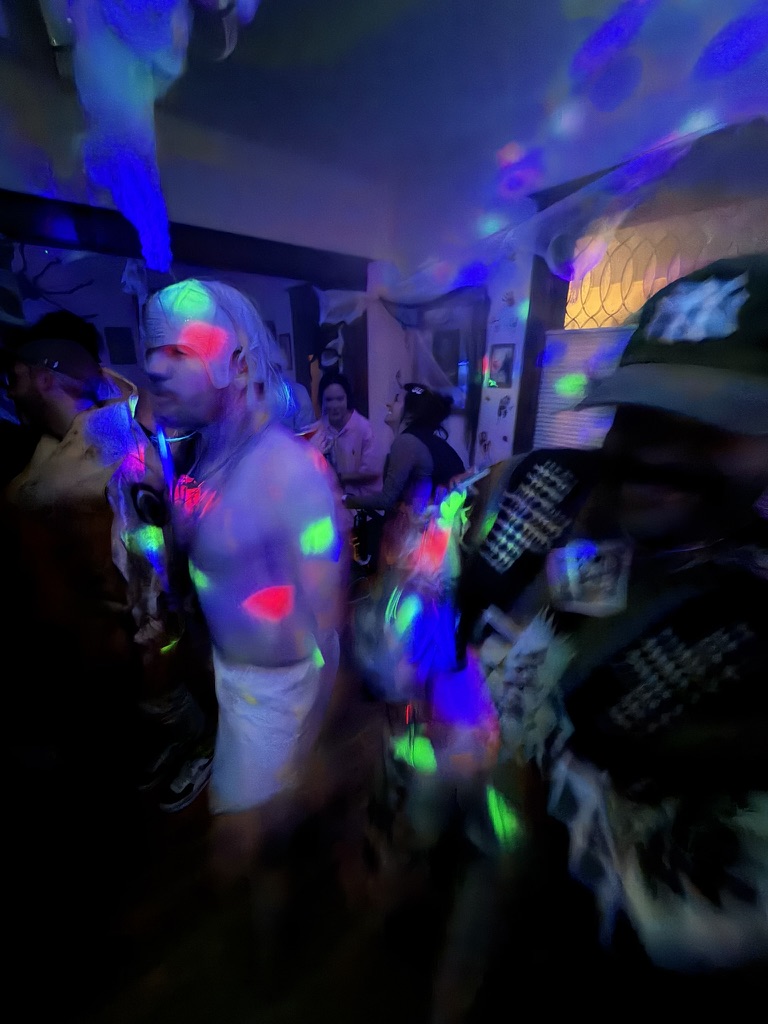 Packed dance floor under blacklight with neon paint splotches